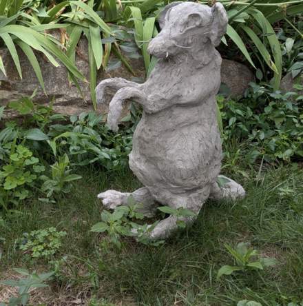 Sculpted rat standing upright among garden plants